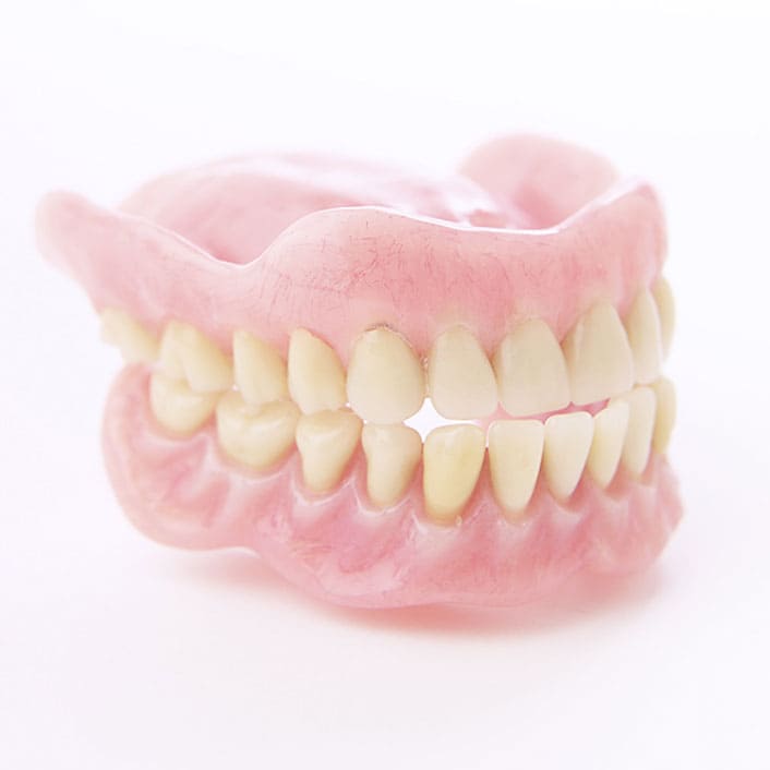 Complete dentures arranged on a neutral background, showcasing their natural appearance.