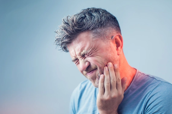 Person holding their jaw in pain, indicating a dental emergency.